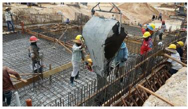 Construction workers wearing safety helmets guiding the pouring of con