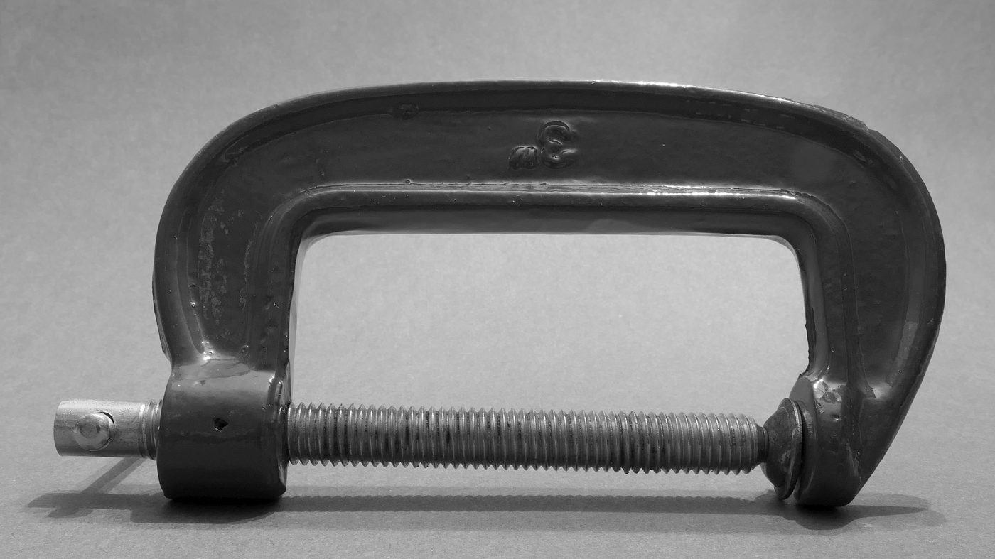 Black metal G-clamp on gray background