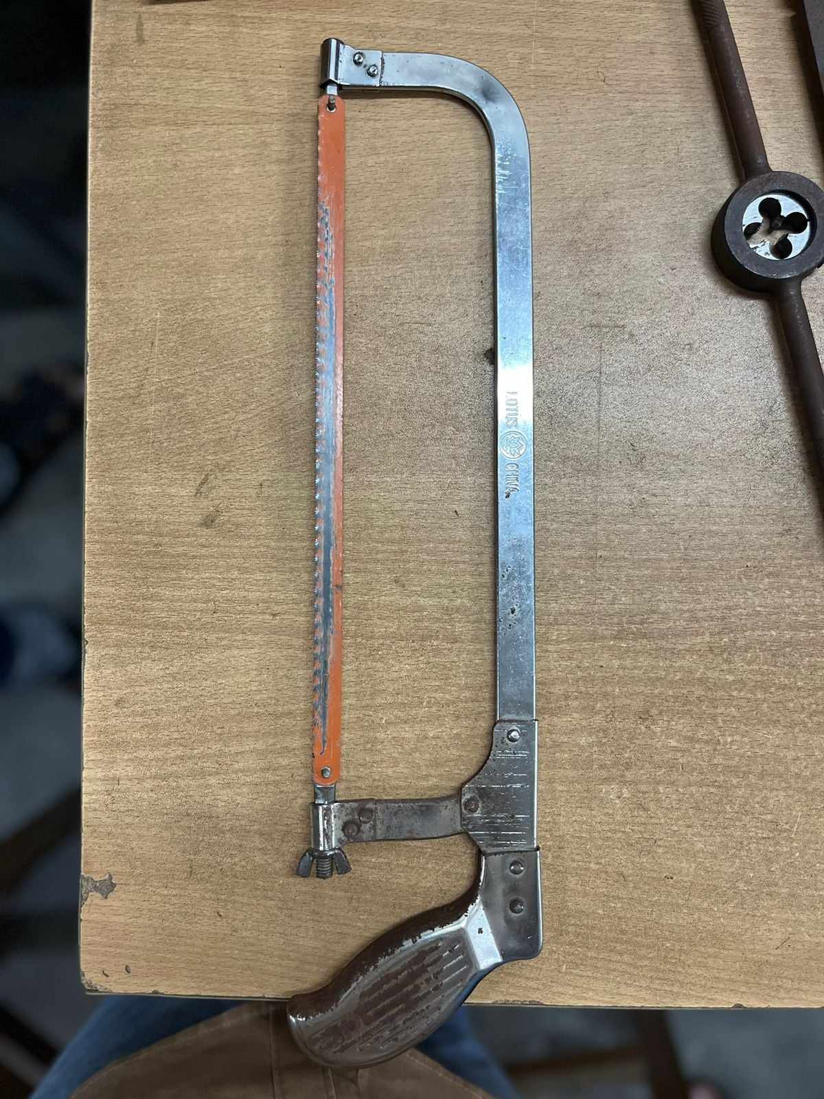 A metal hacksaw with an orange blade