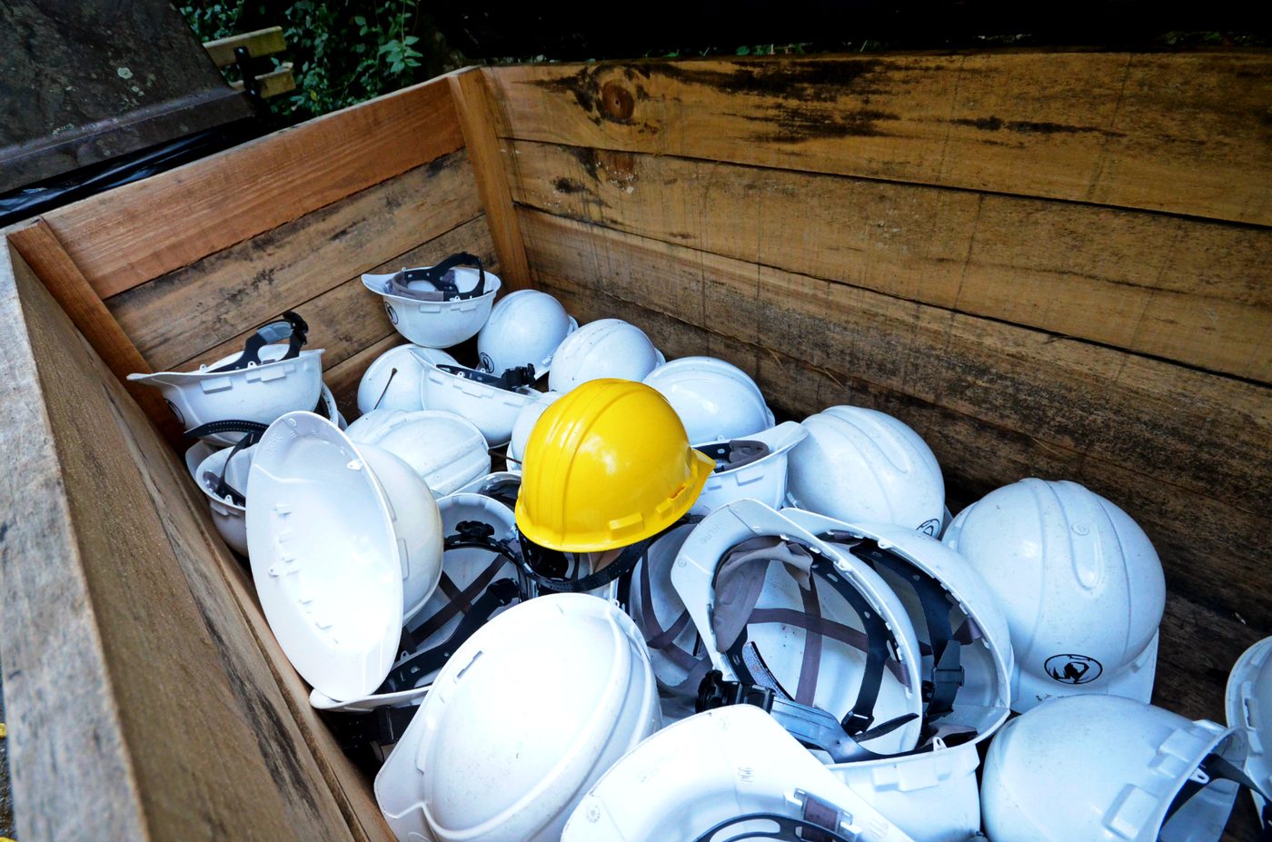 Yellow and white hard hats in a wooden crate