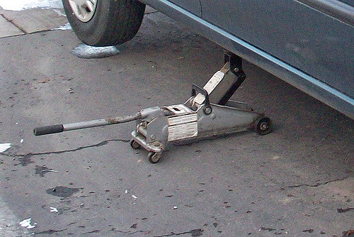 Hydraulic floor jack lifting a car