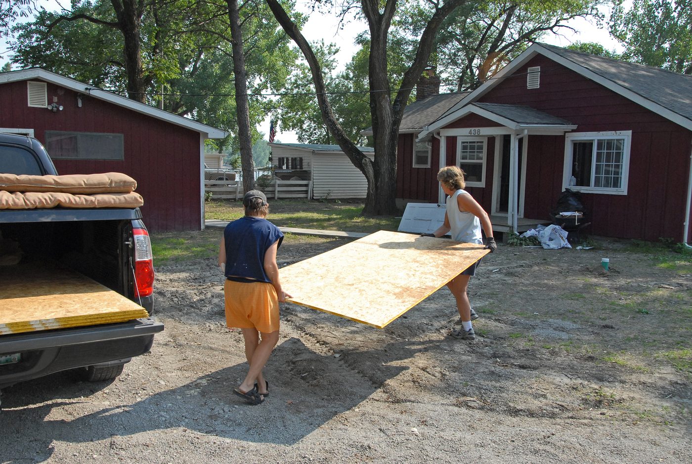 Two people carrying a particle board sheet