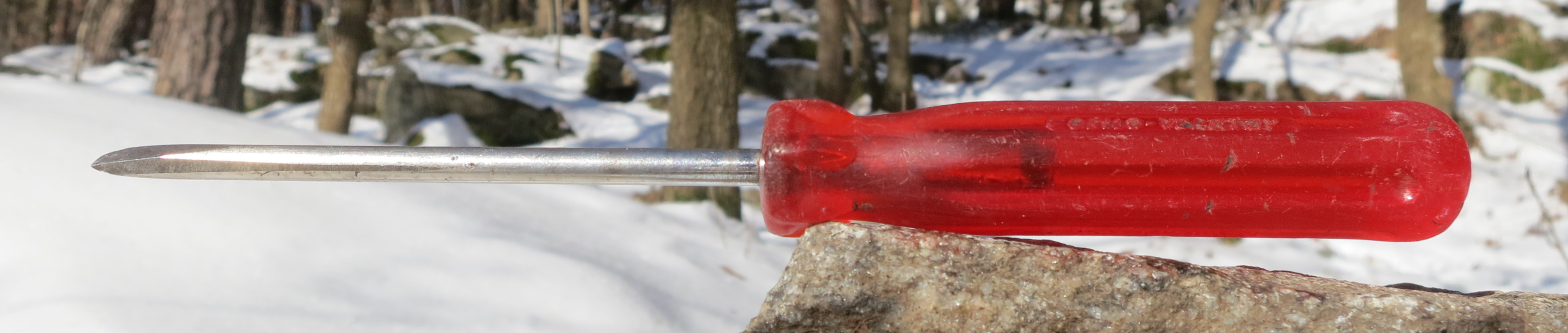 Red-handled screwdriver on rock outdoors