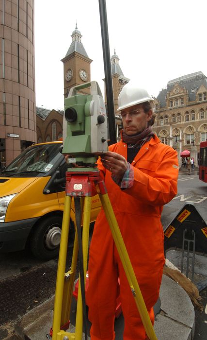 Surveyor using a total station on site